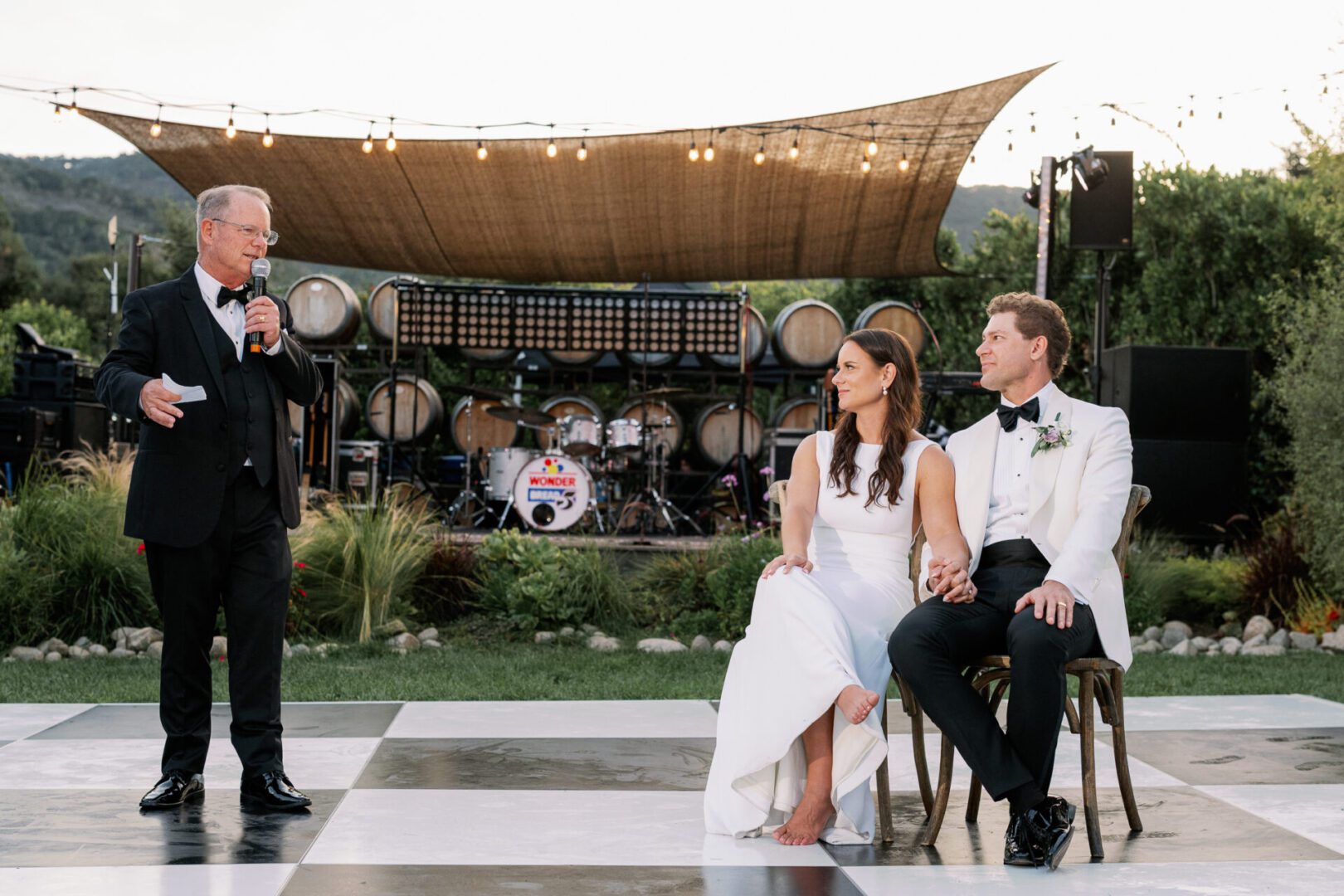 Wedding speech with couple seated outdoors.
