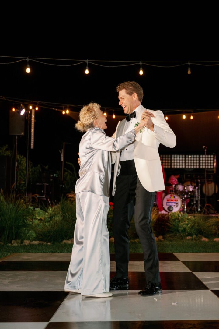 Couple dancing on checkered floor outdoors.